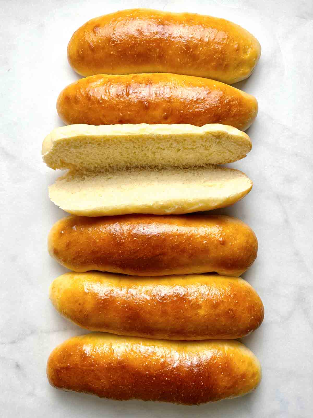 close up of hot dog buns with one cut in half and opened.