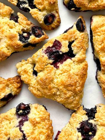 close up of blueberry scones on parchment paper.