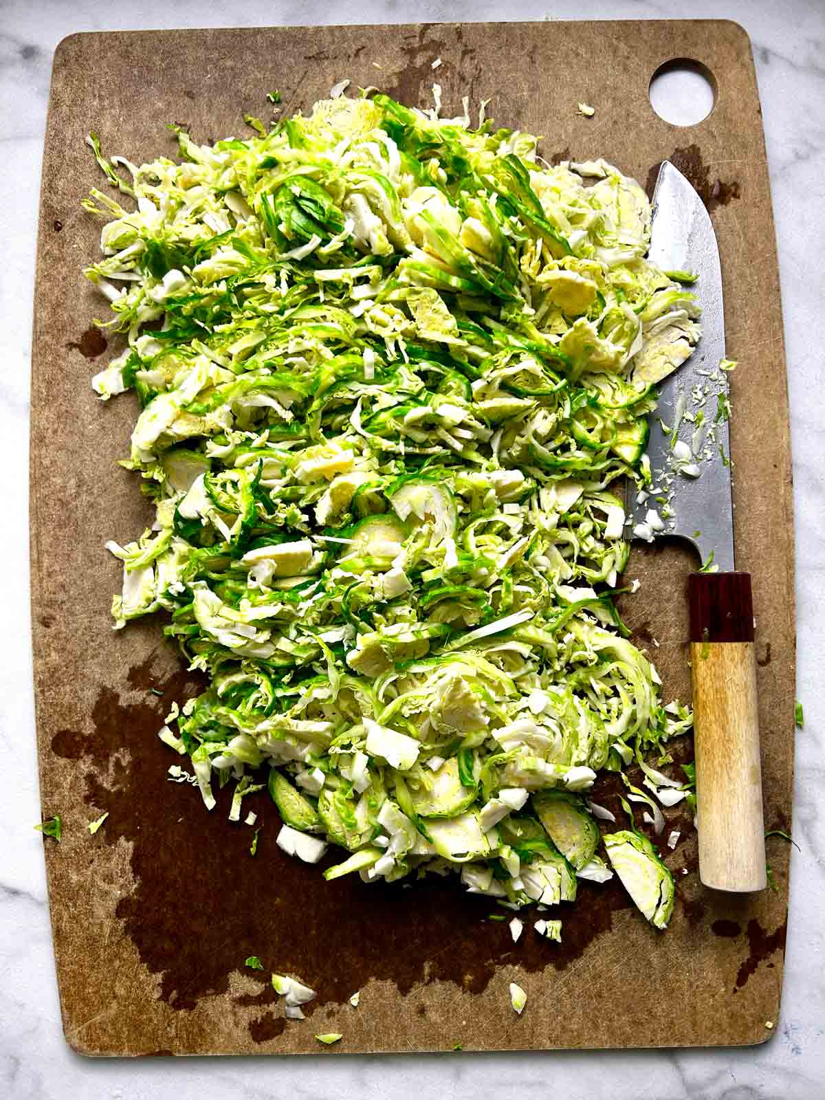 Brussels sprouts cut thinly on cutting board.