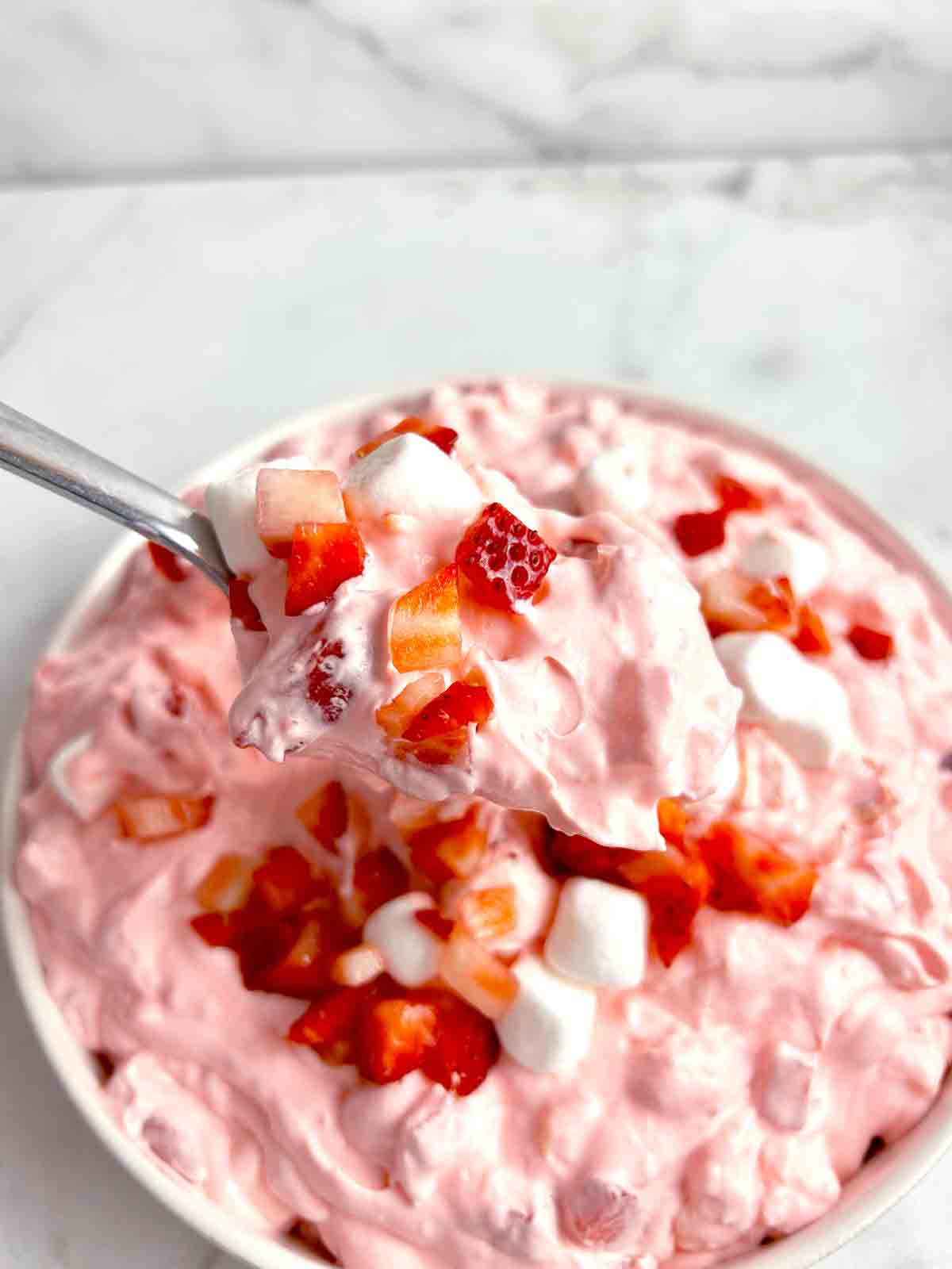 spoon lifting strawberry fluff from bowl.