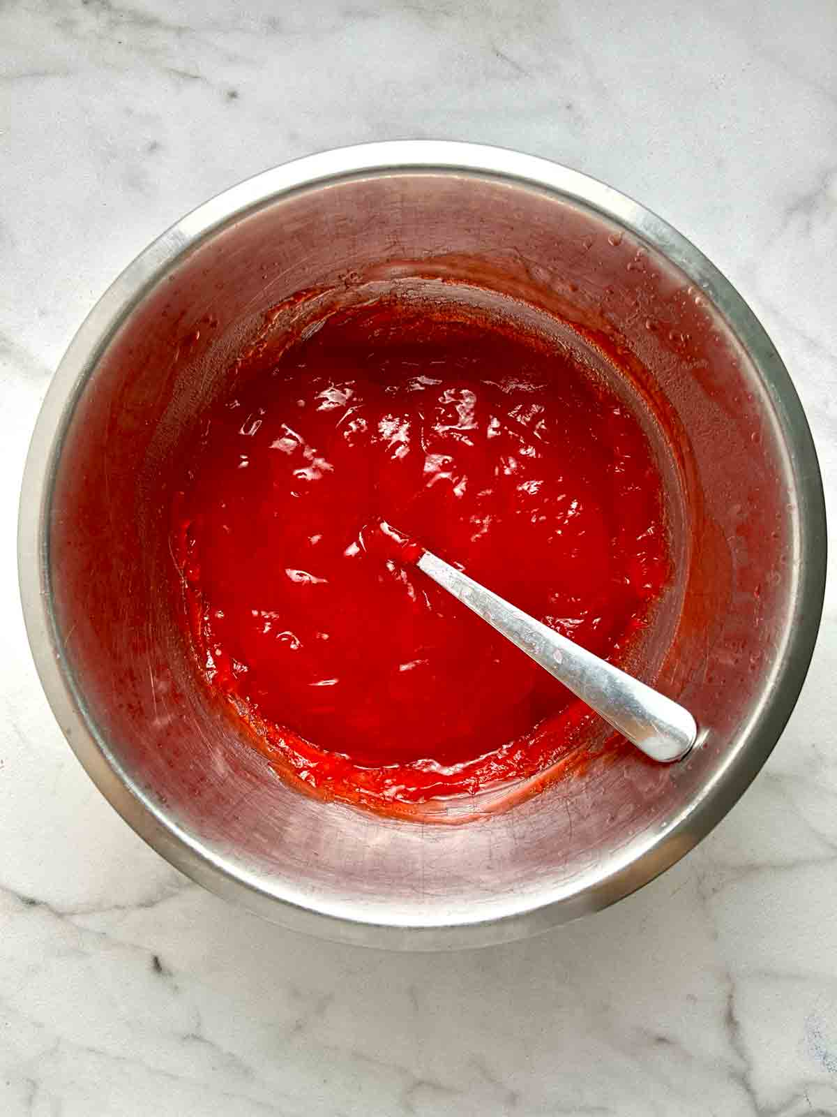 strawberry gelatin mixture thickened in bowl.