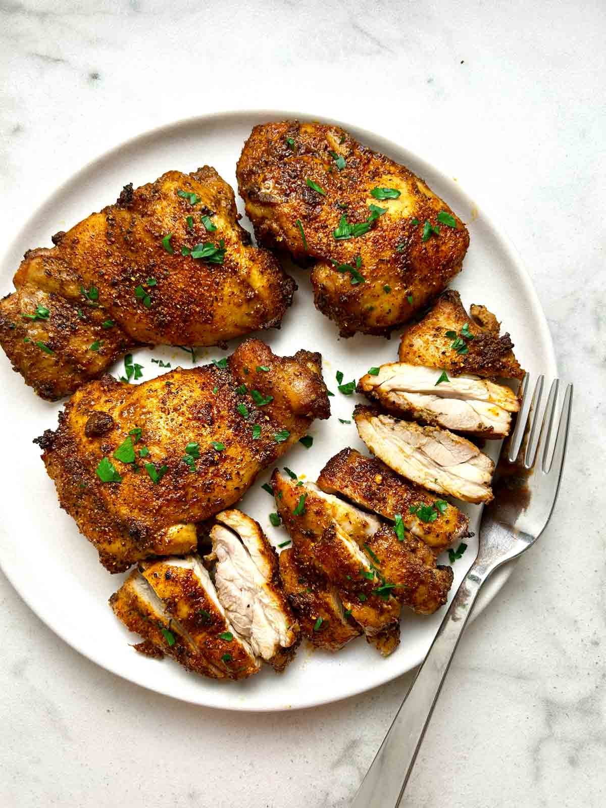 plate of air-fried chicken thighs; some are cut into pieces.