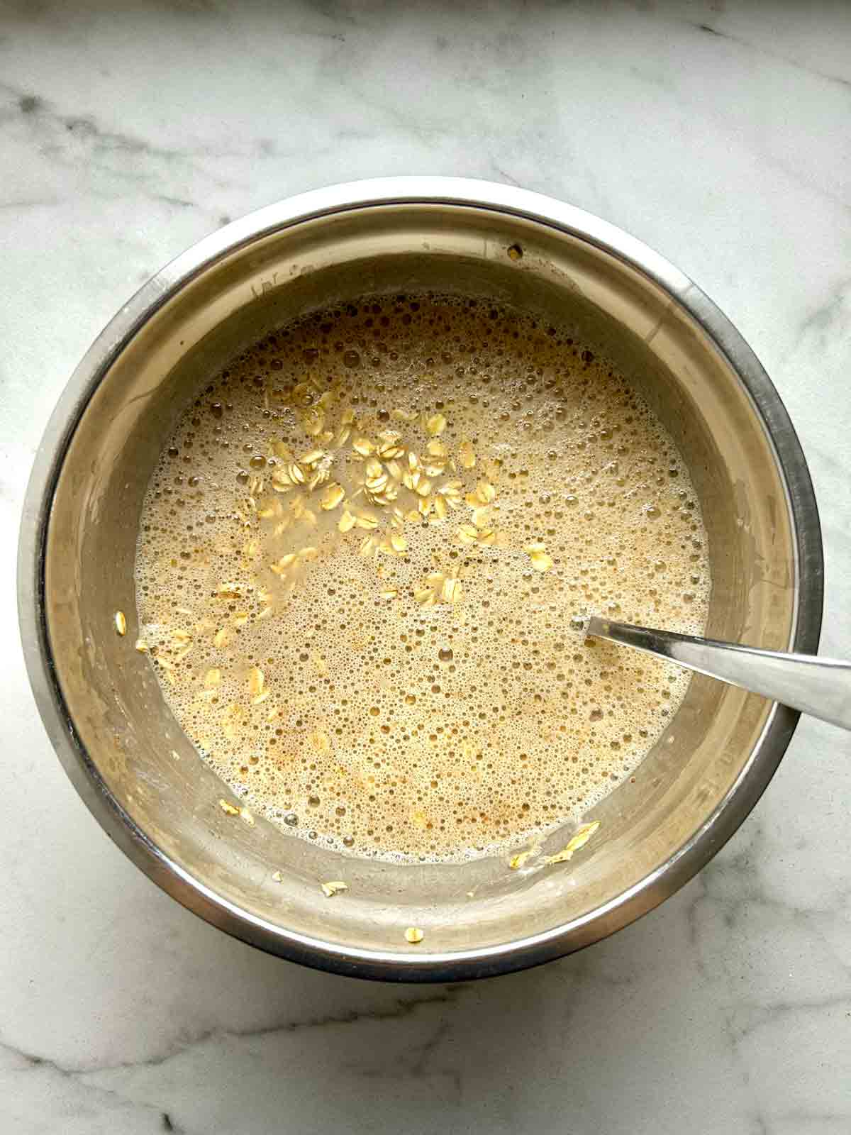 oats mixed with other ingredients in metal bowl.