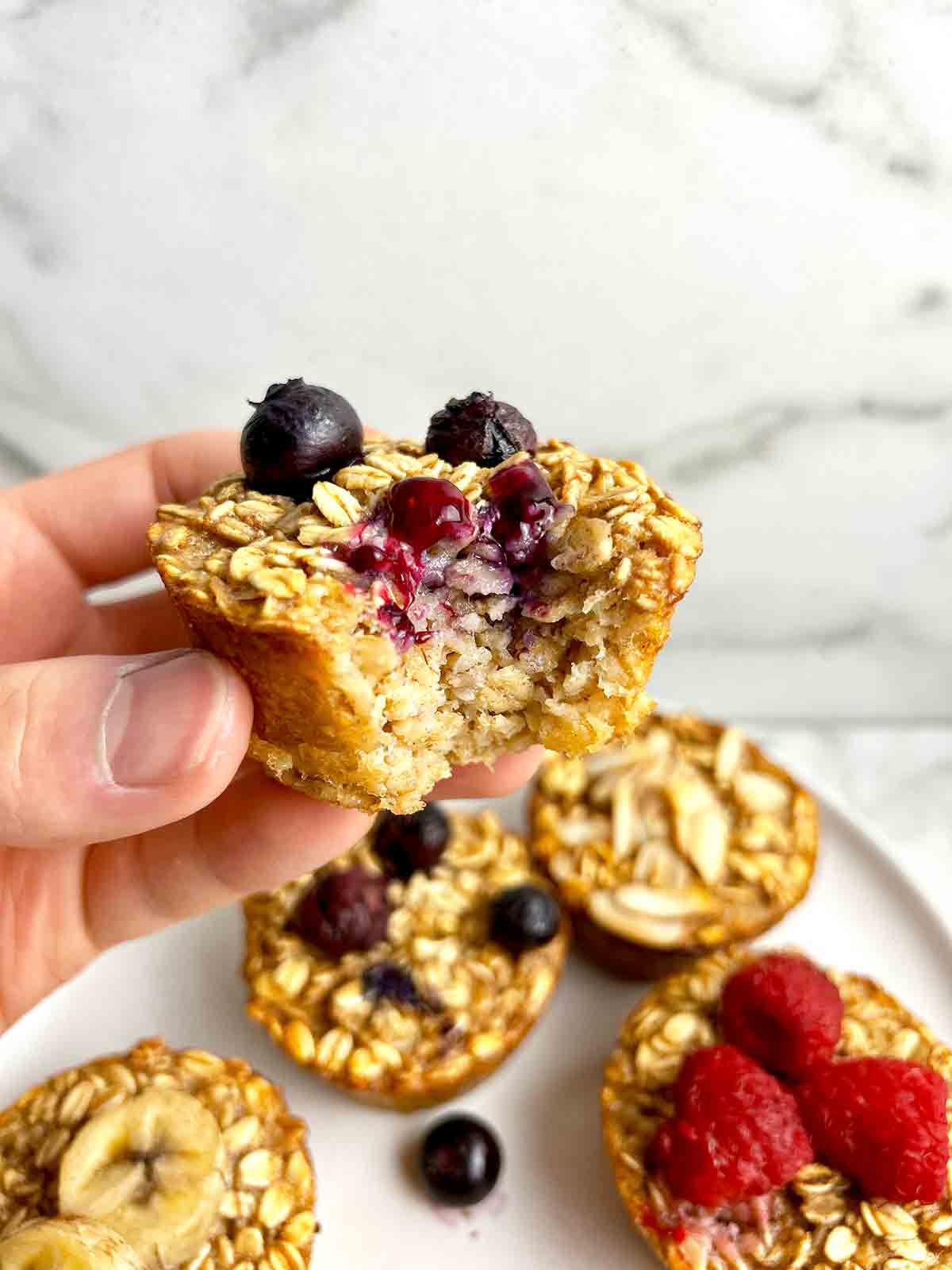 hand holding blueberry oatmeal cup with bite taken out of it.