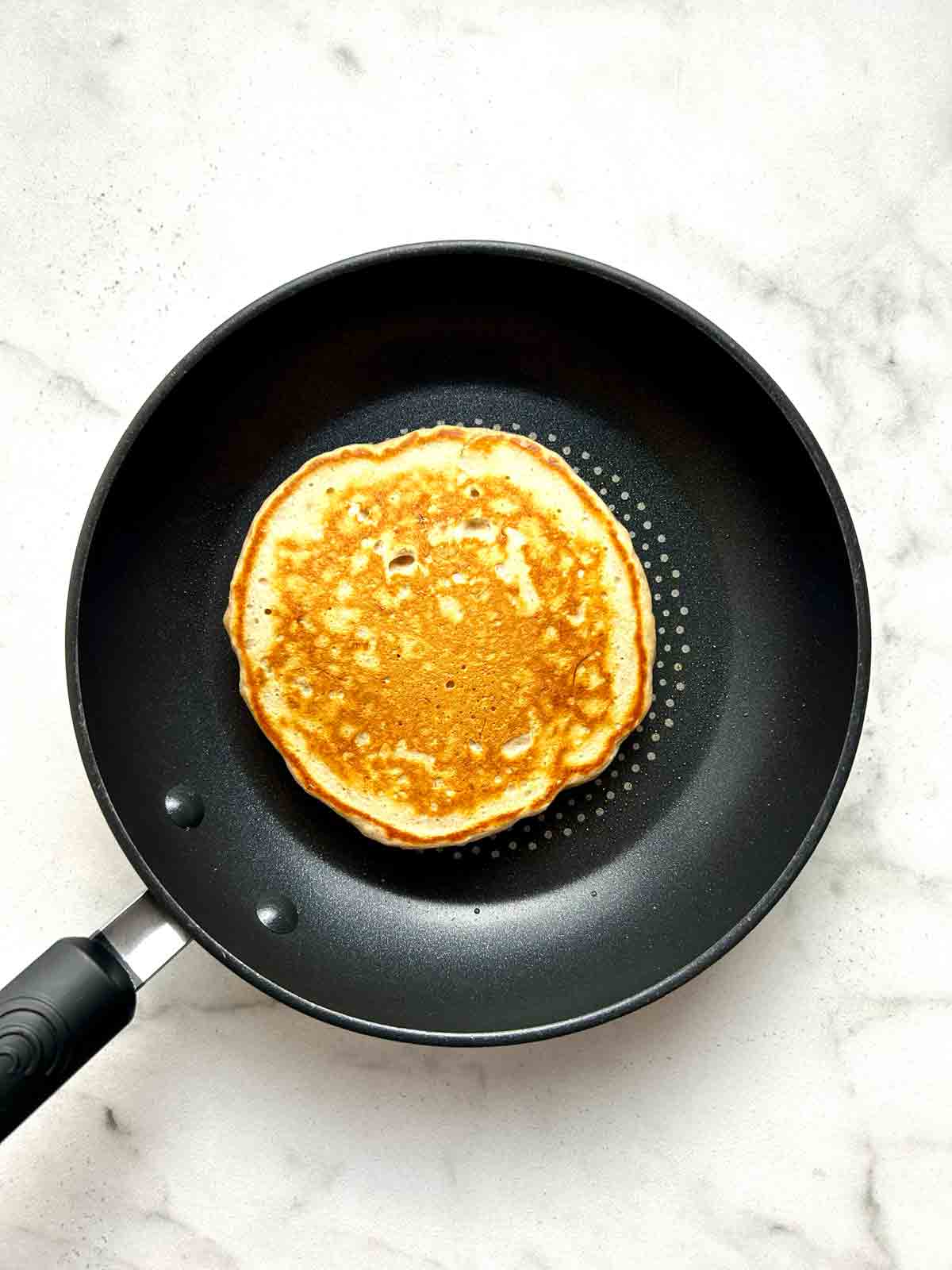 banana pancake cooked in pan; golden brown.