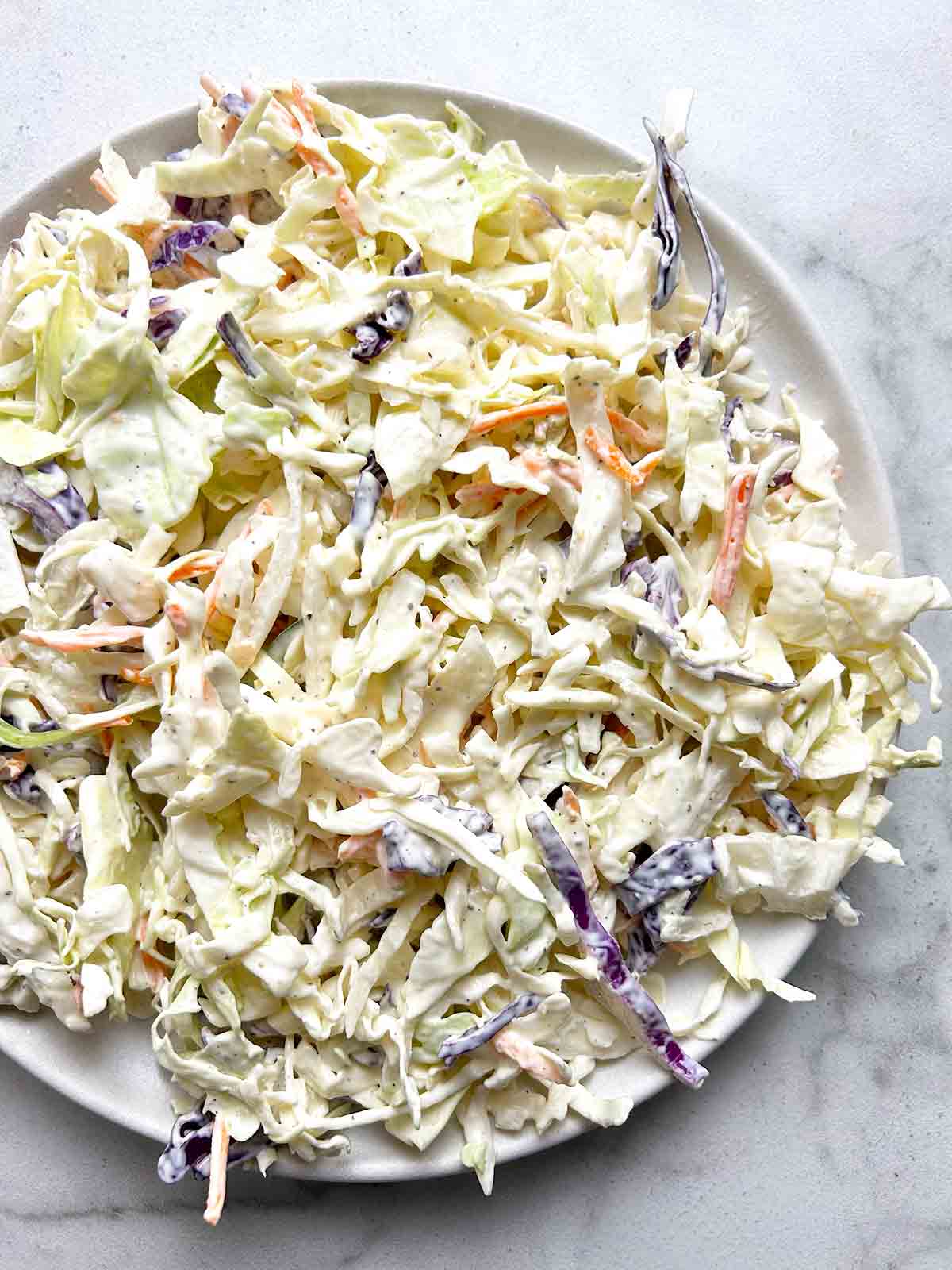coleslaw on plate with extra dressing drizzled on top.