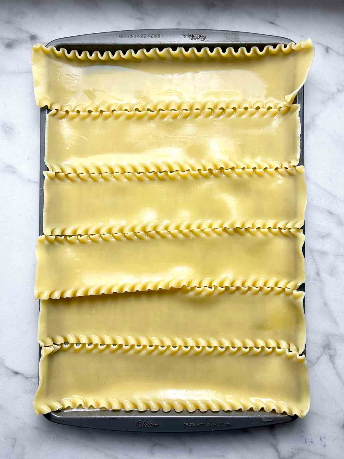 cooked lasagna noodles spread on baking sheet.