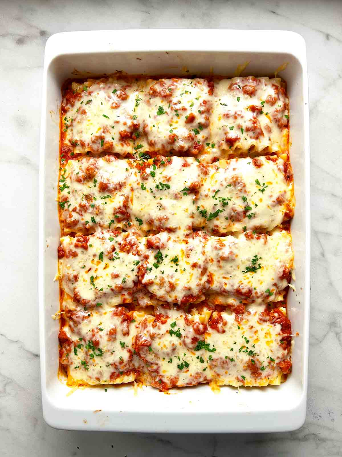 lasagna roll ups done baking in baking dish; parsley sprinkled on top.
