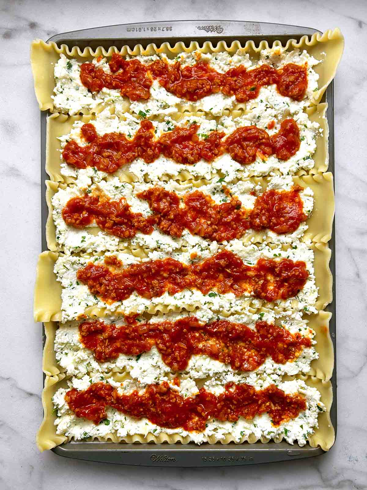 meat sauce and ricotta filling spread onto 6 lasagna noodles on baking sheet.