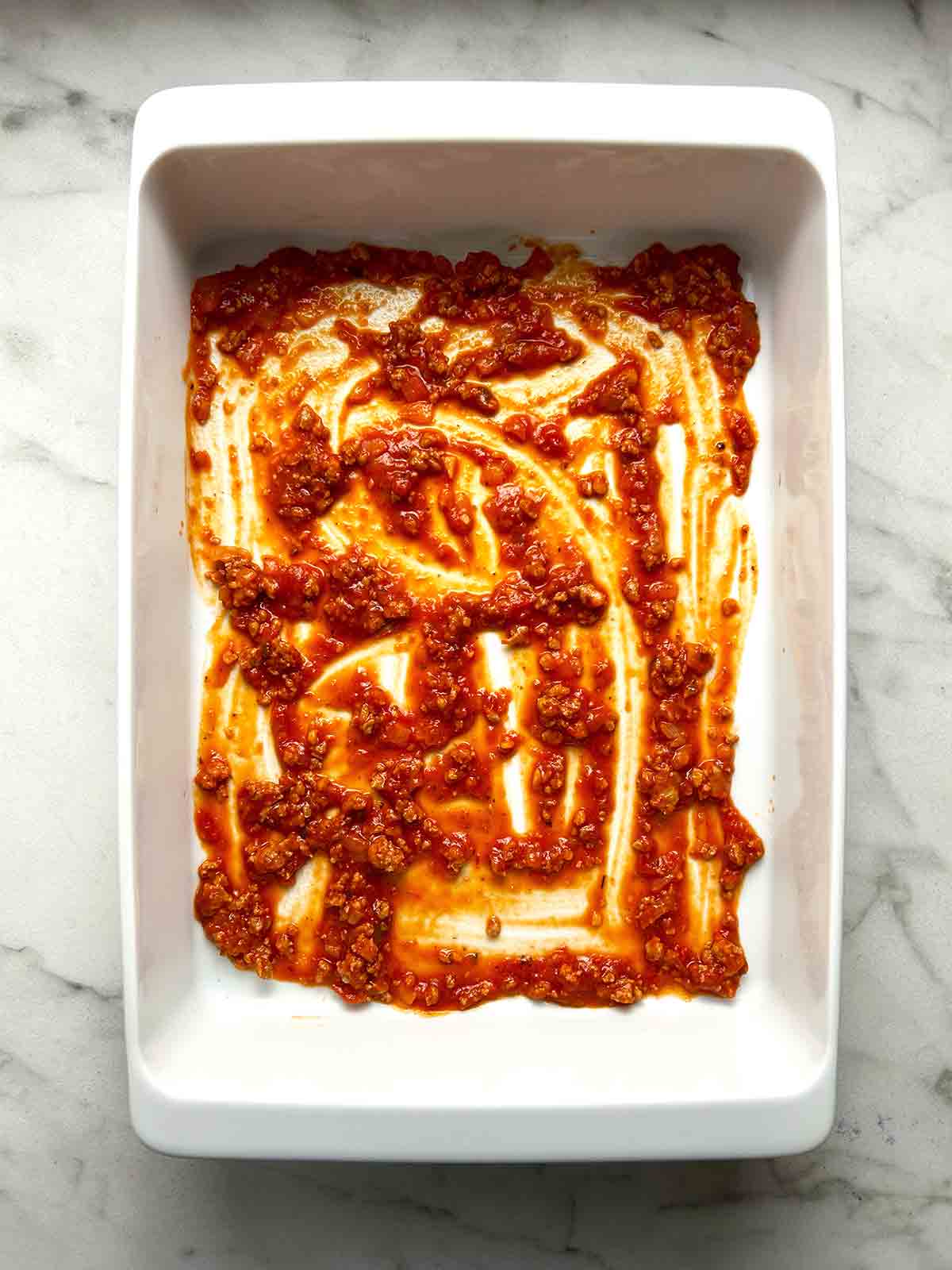 meat sauce spread in bottom of baking dish.