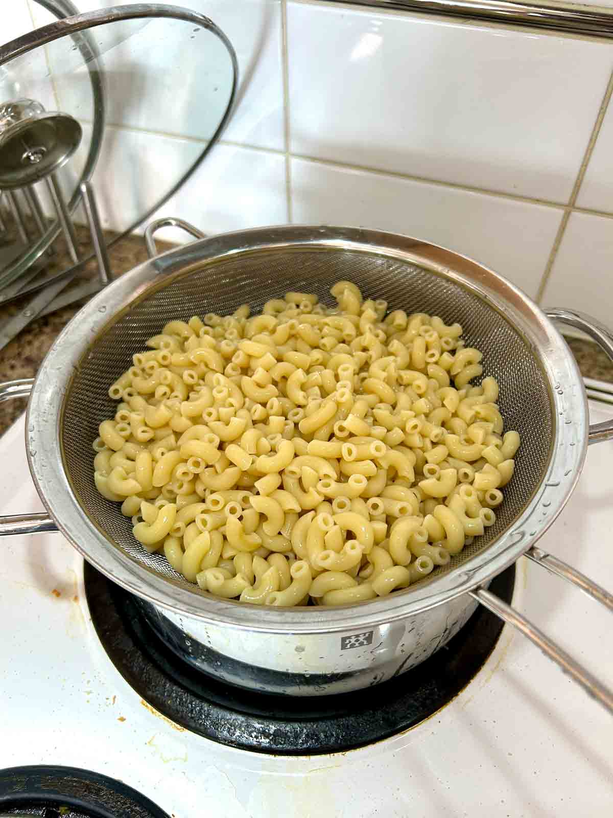 cooked macaroni draining over pot.
