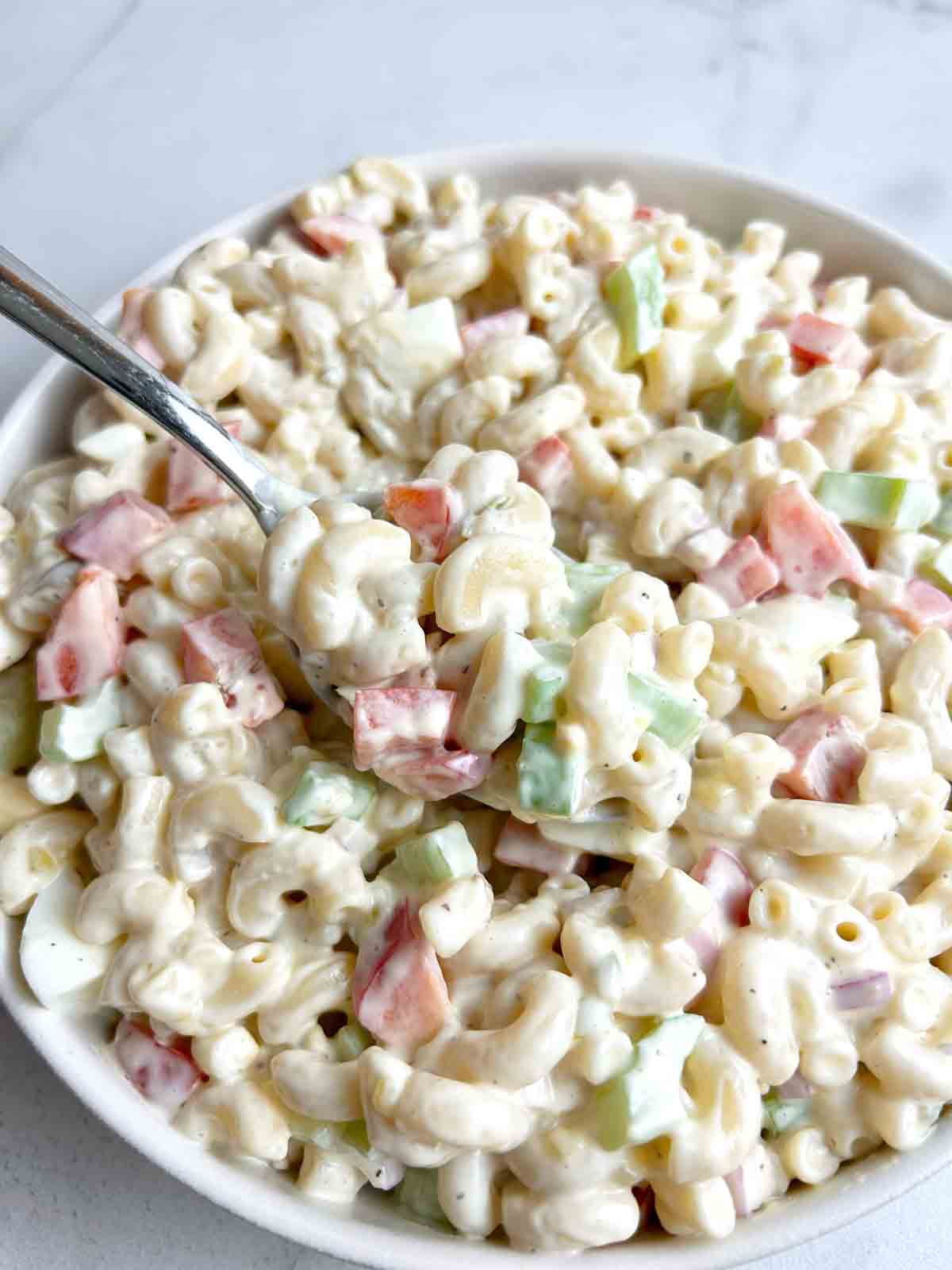spoon lifting macaroni salad from bowl.