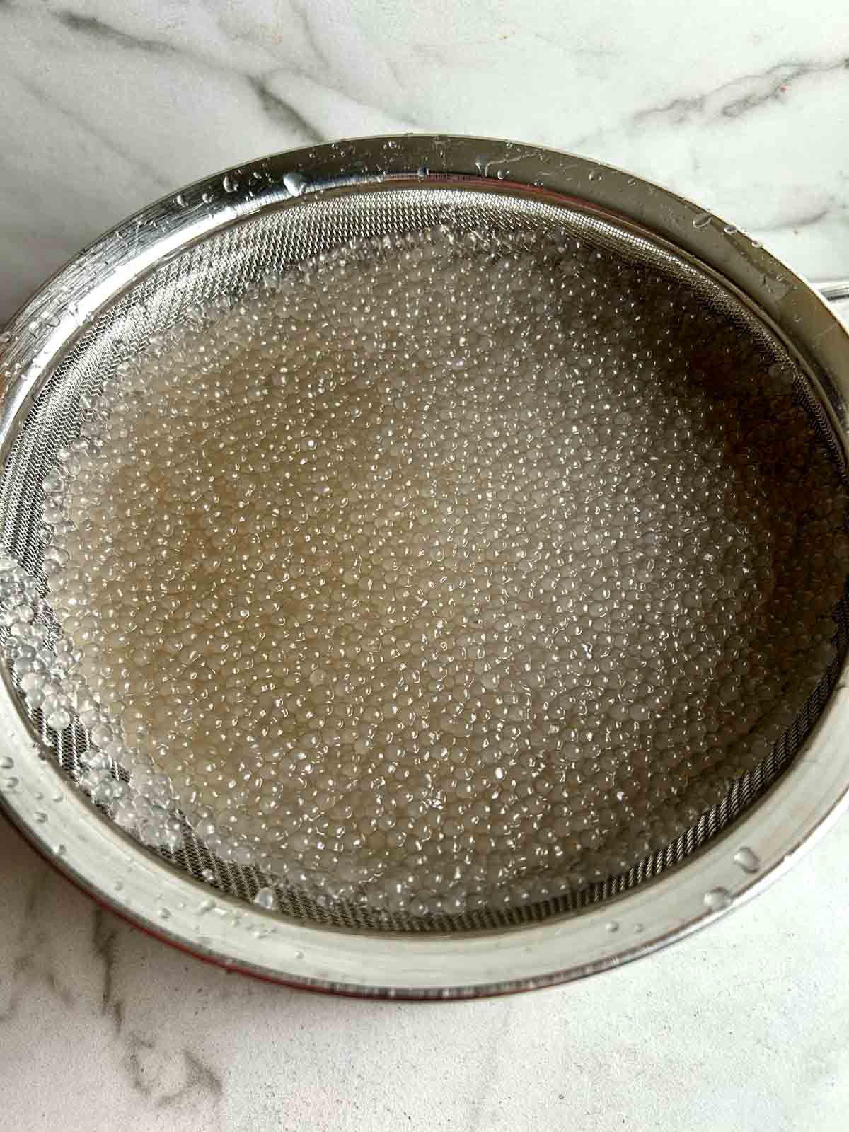 cooked tapioca draining in colander.
