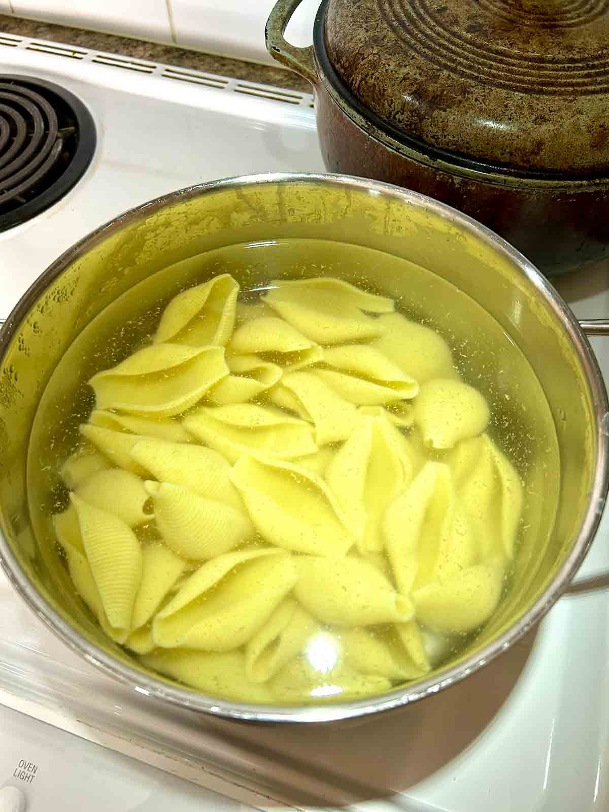jumbo shells cooking in pot of water.