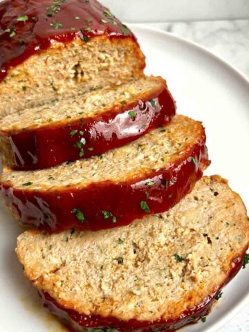 close up of meatloaf sliced into thick pieces on plate.