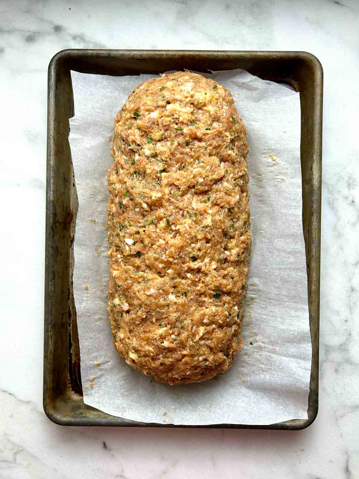 meat mixture shaped into loaf on baking sheet.