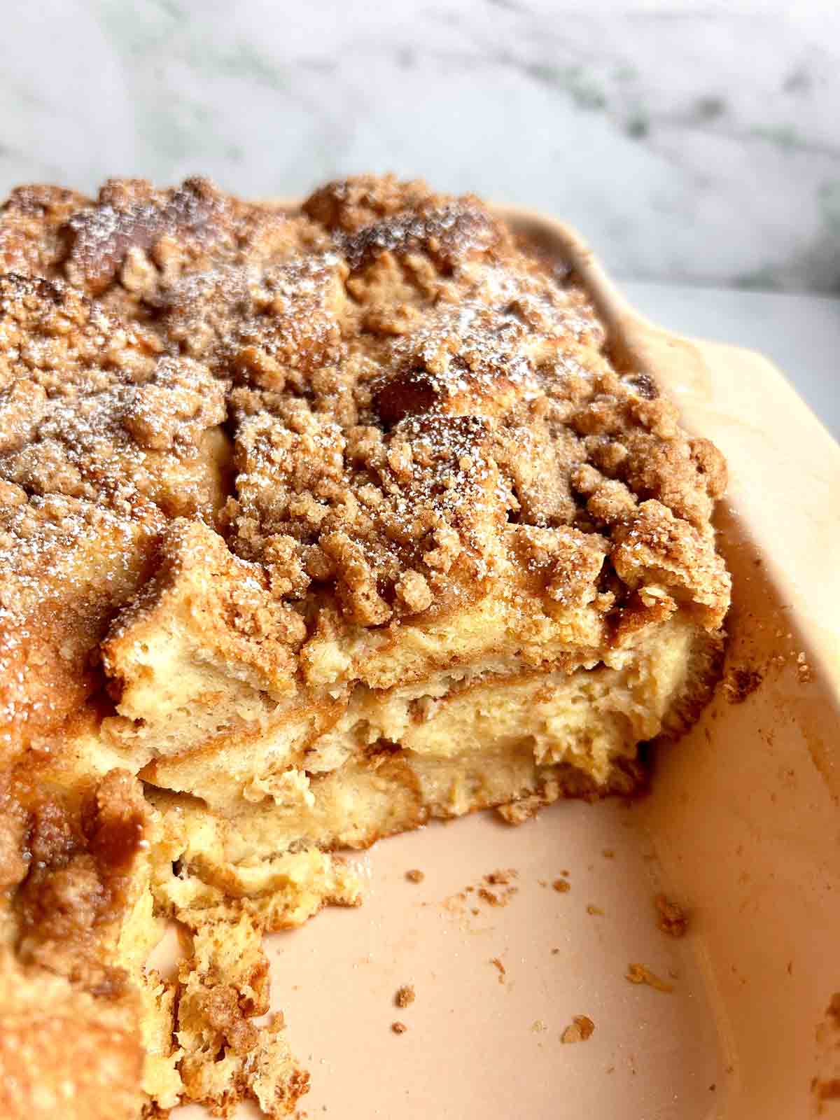 close up of slice of french toast casserole in baking dish.