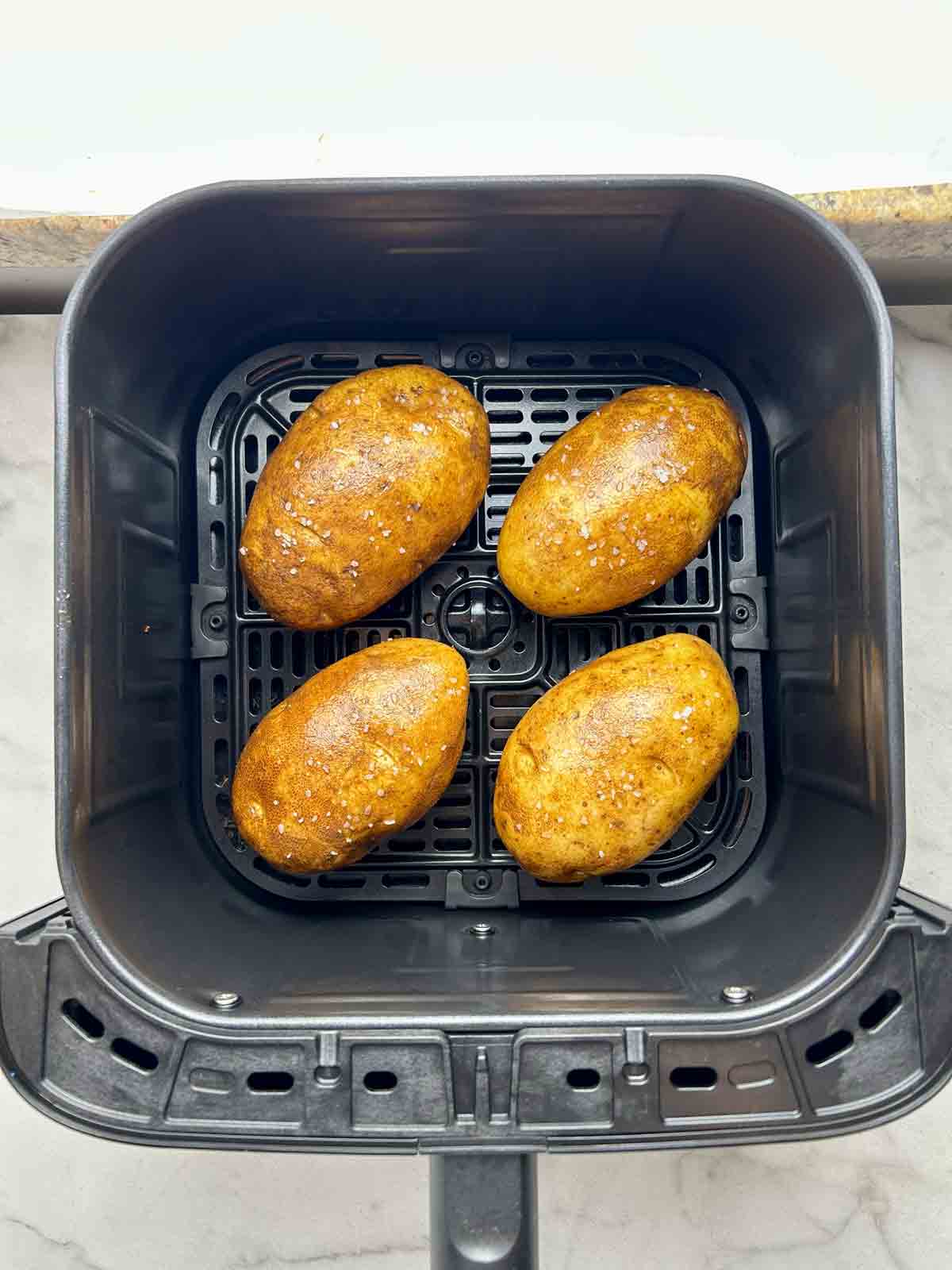 potatoes arranged in air fryer basket.