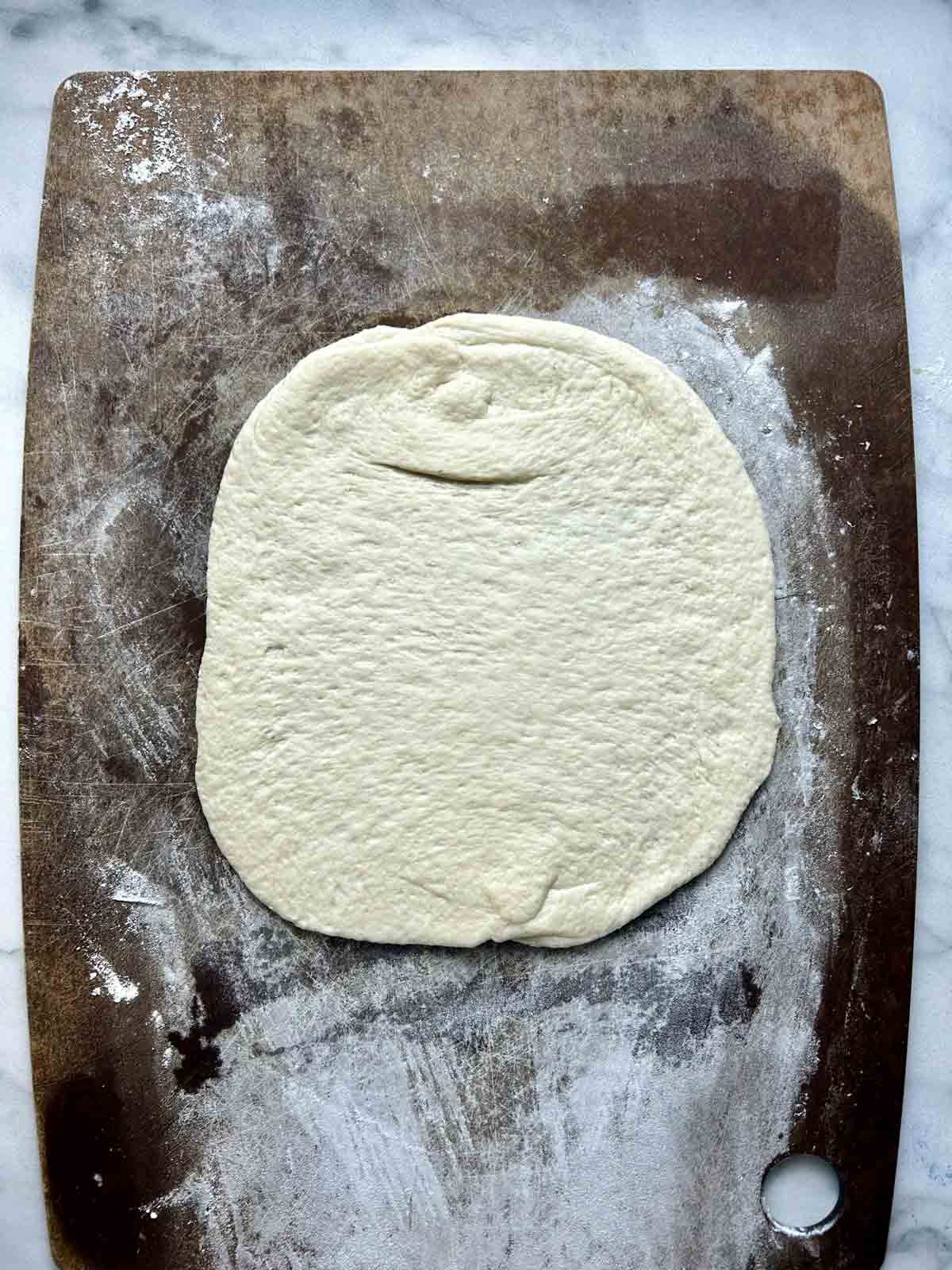 dough rolled into circle on cutting board.