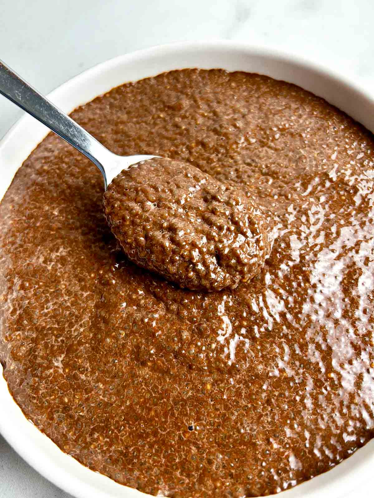 spoon lifting chocolate chia pudding from bowl.