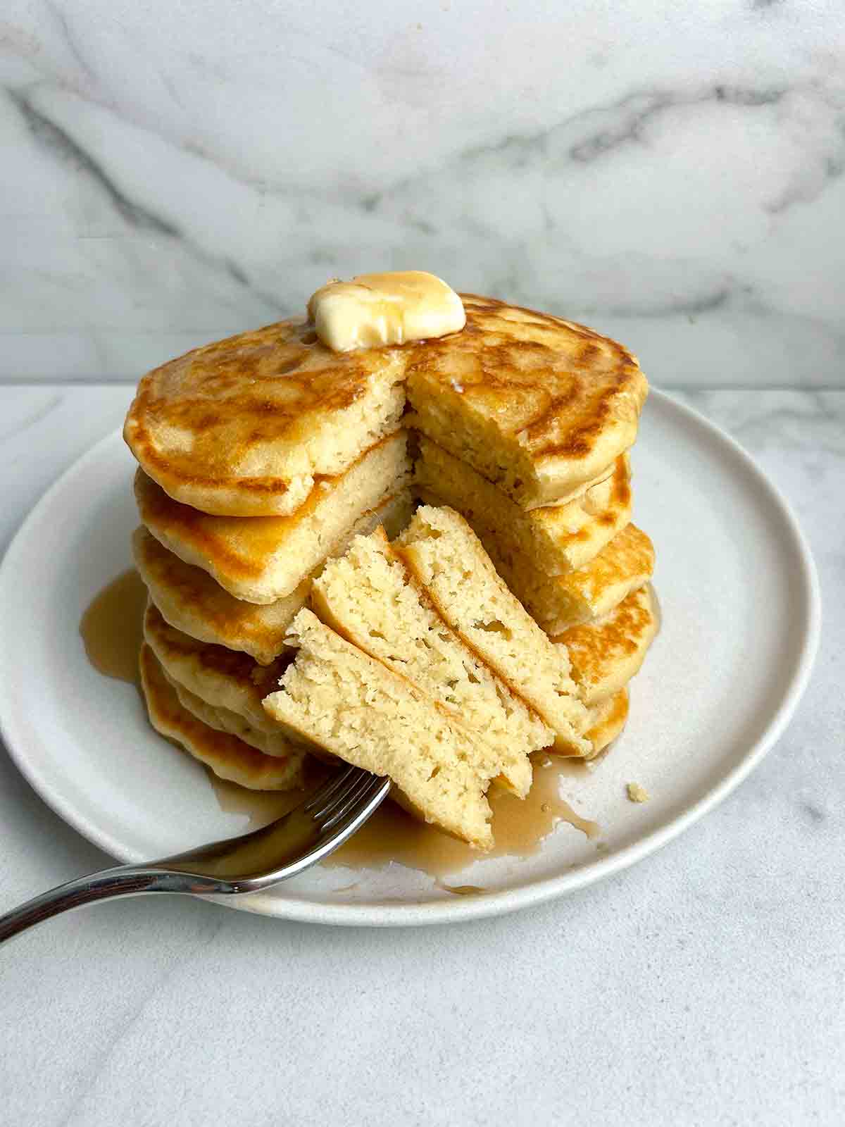 stack of pancakes with section cut through all of them to show the fluffy inside.