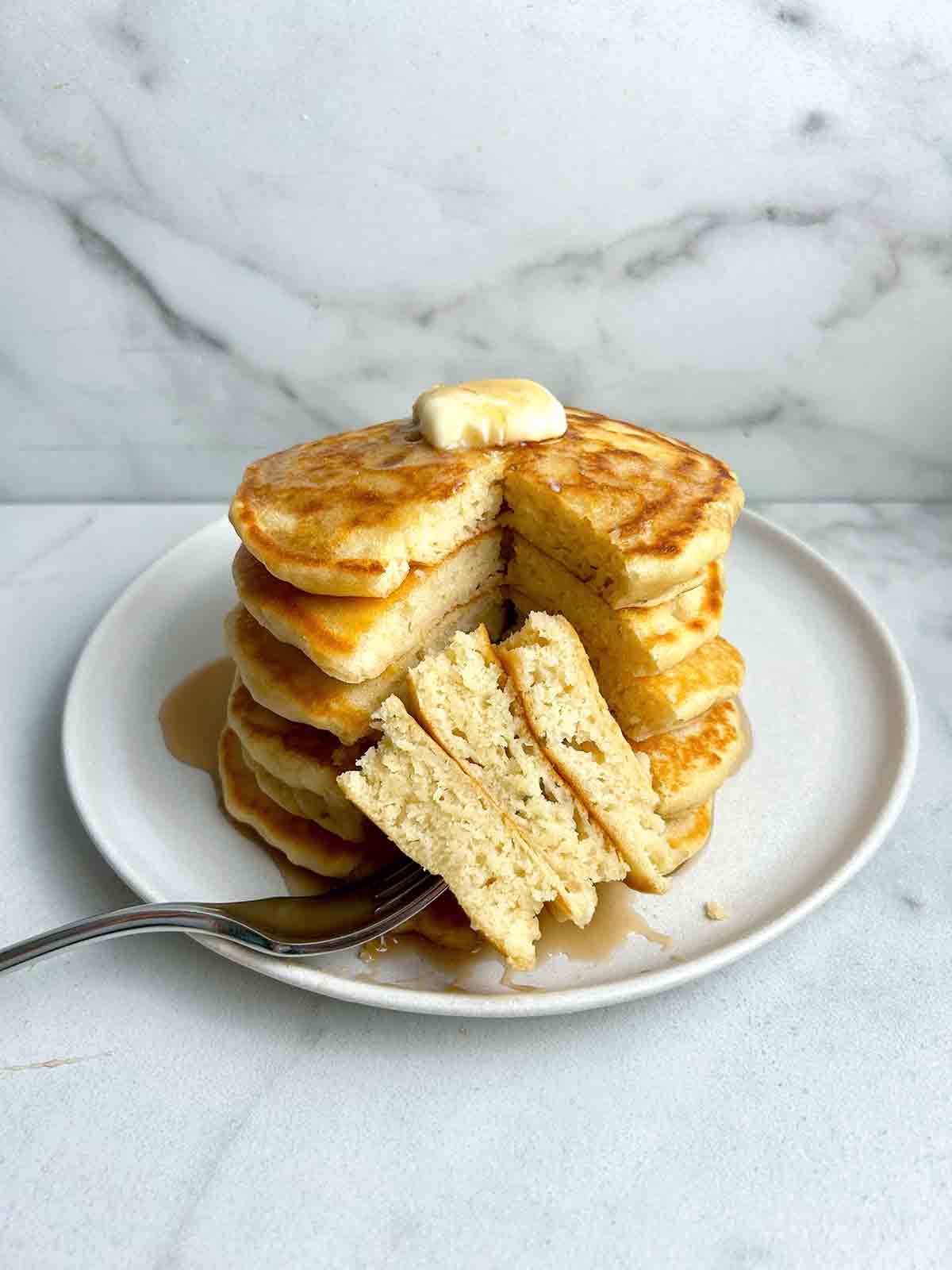 stack of pancakes with section cut through all of them to show the fluffy inside.