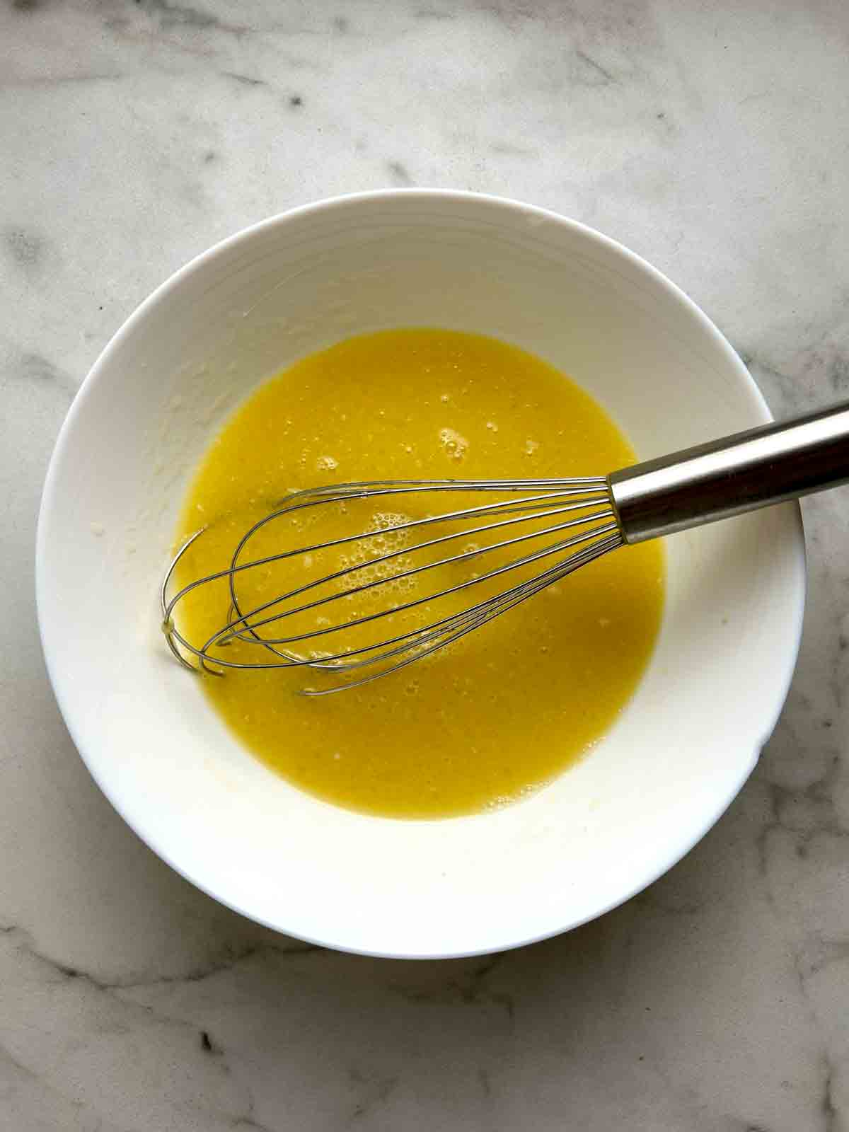 wet mixture whisked in white bowl.