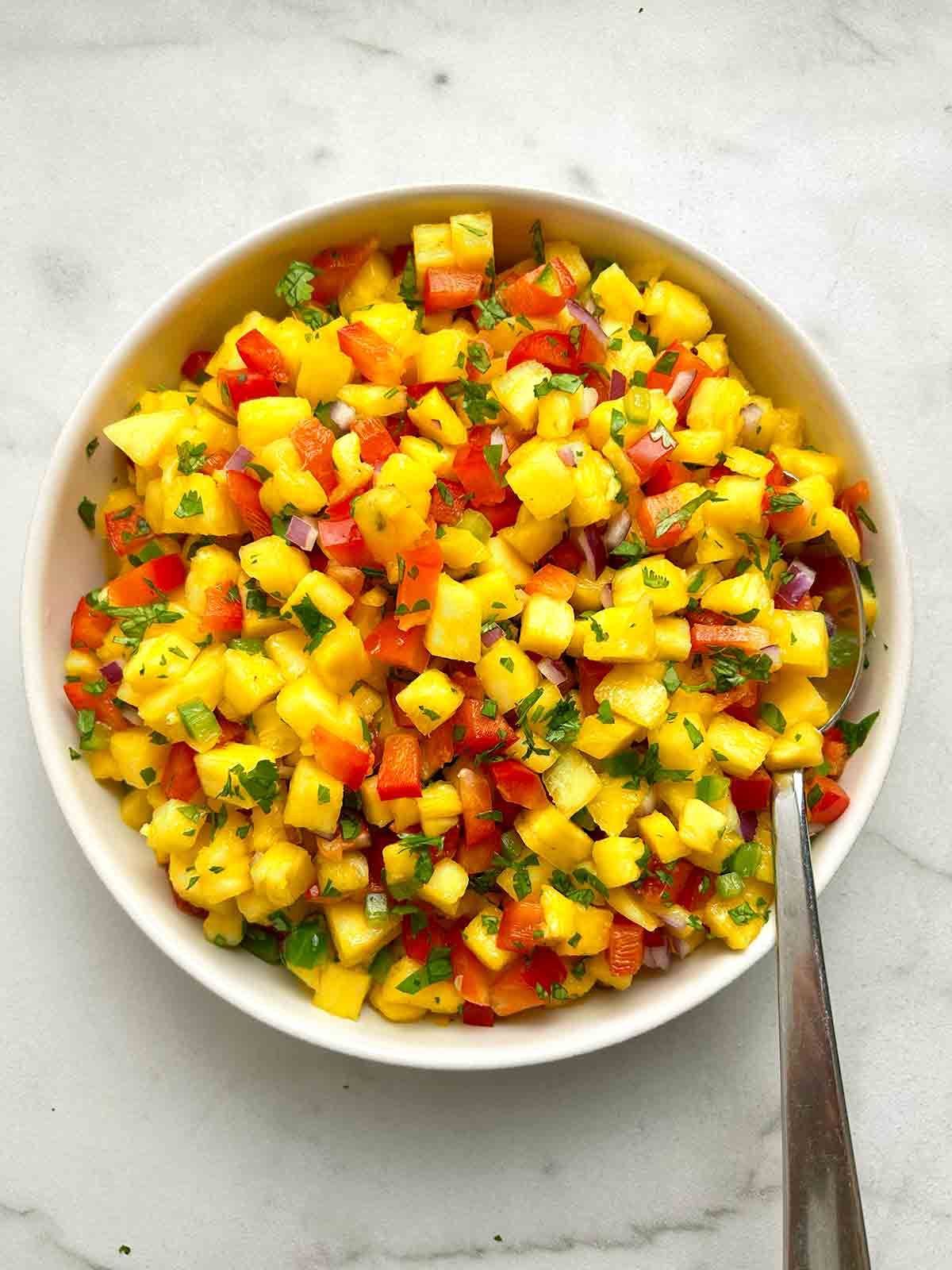 bowl of pineapple salsa with spoon.