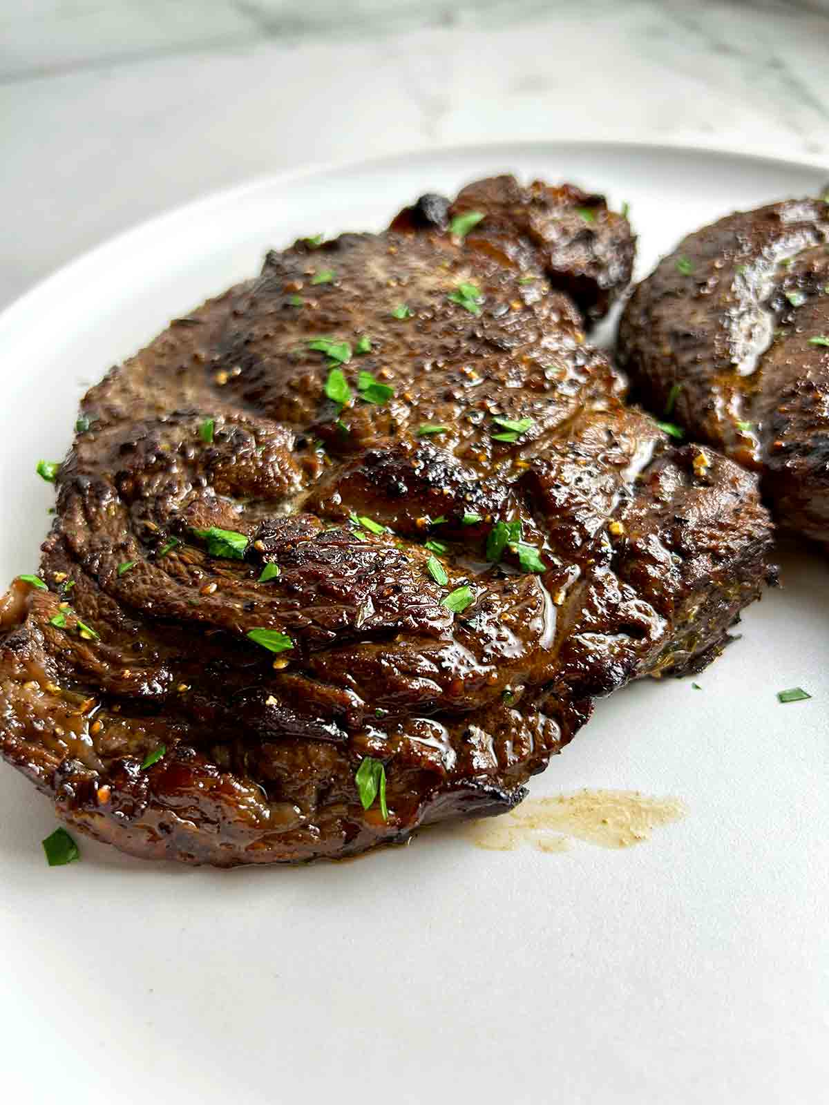 cooked steak with parsley on top.