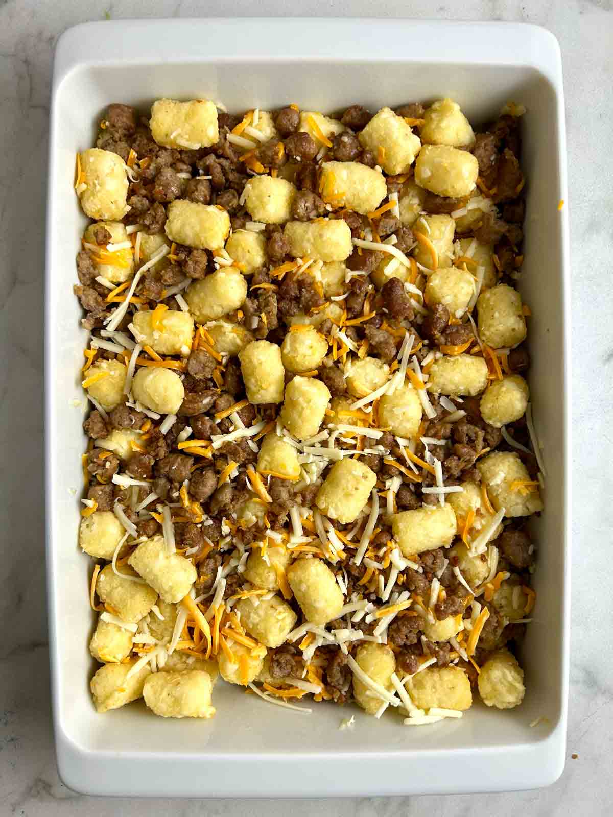 tater tots, sausage, and cheese spread in casserole dish.