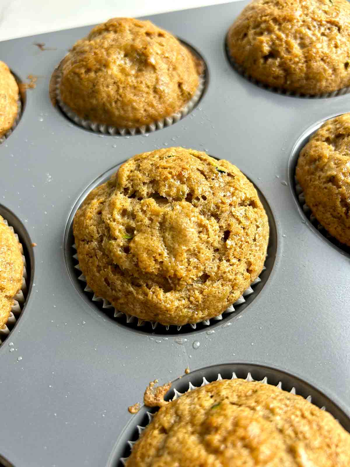 close up of zucchini banana muffin in muffin pan.