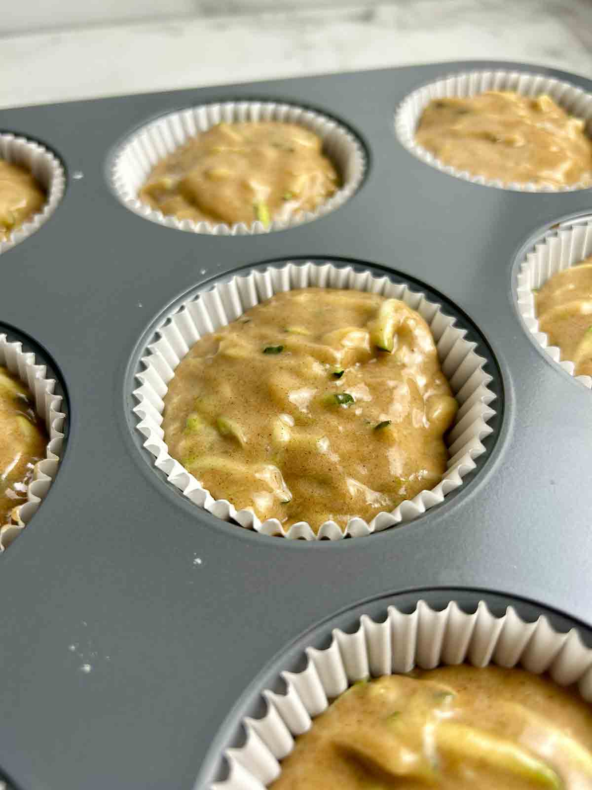 close up of batter spooned into muffin cup liner.