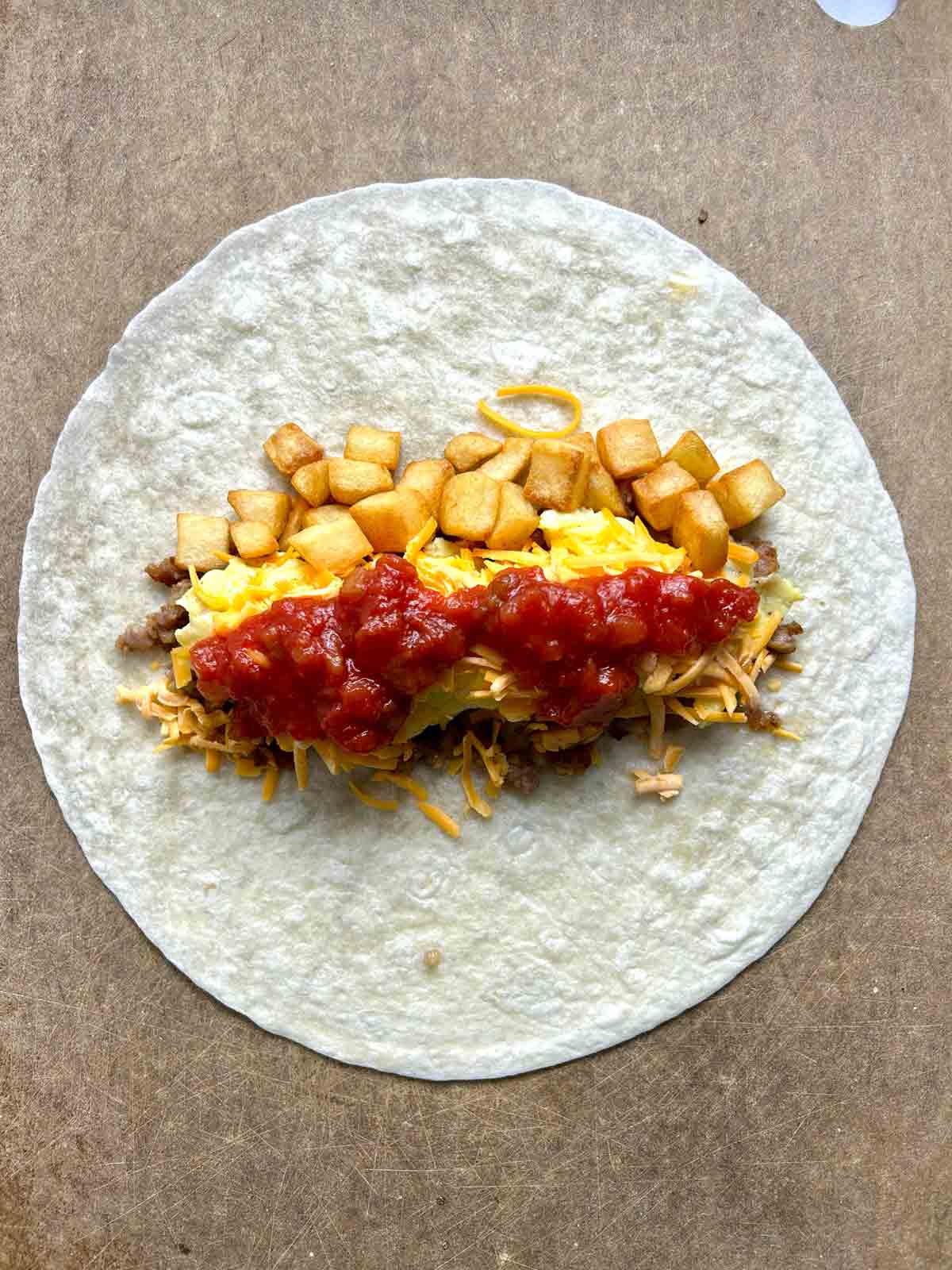 sausage, egg, cheese, and hash browns added of center of tortilla.