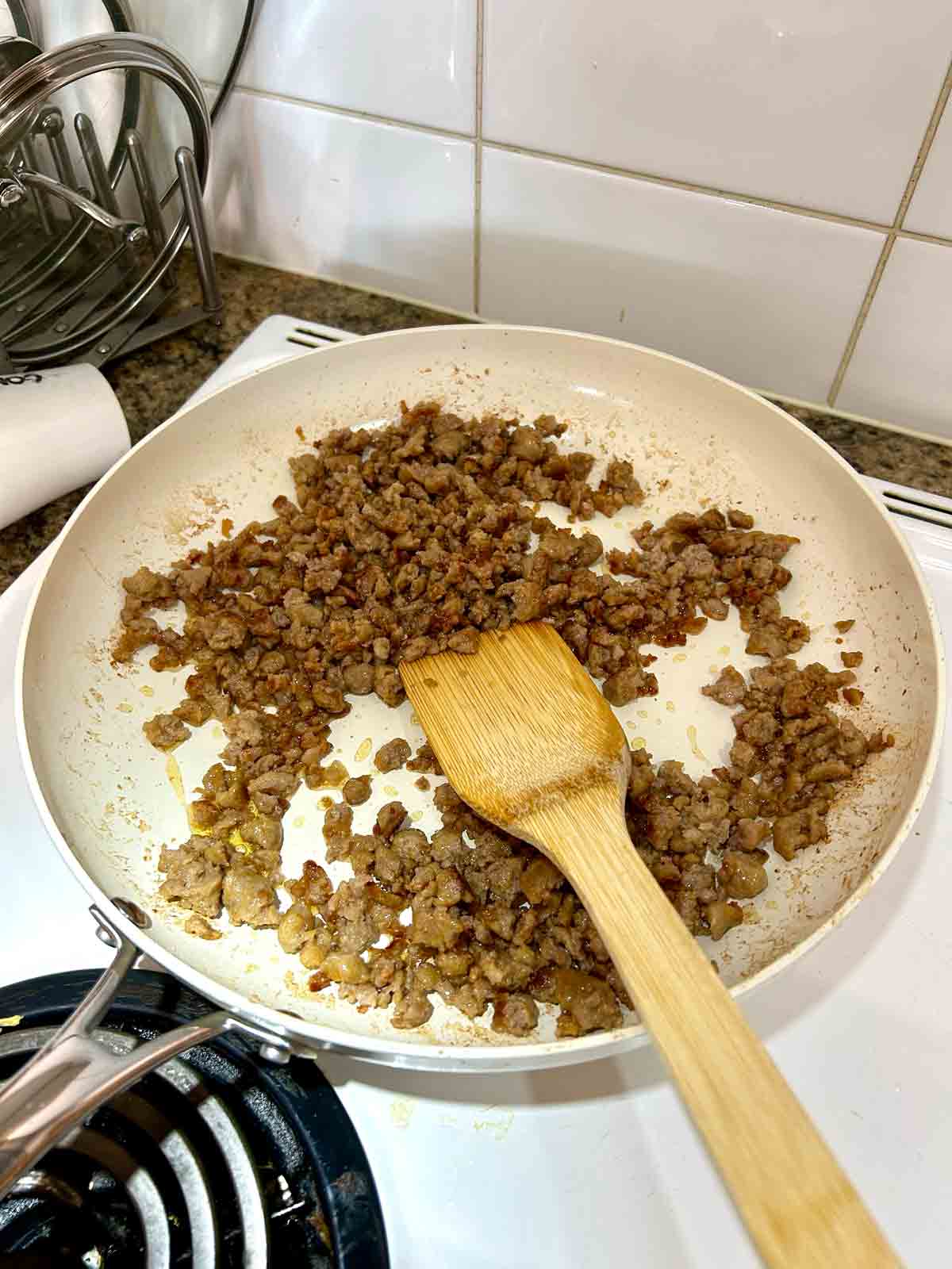 sausage being cooked in large white skillet.