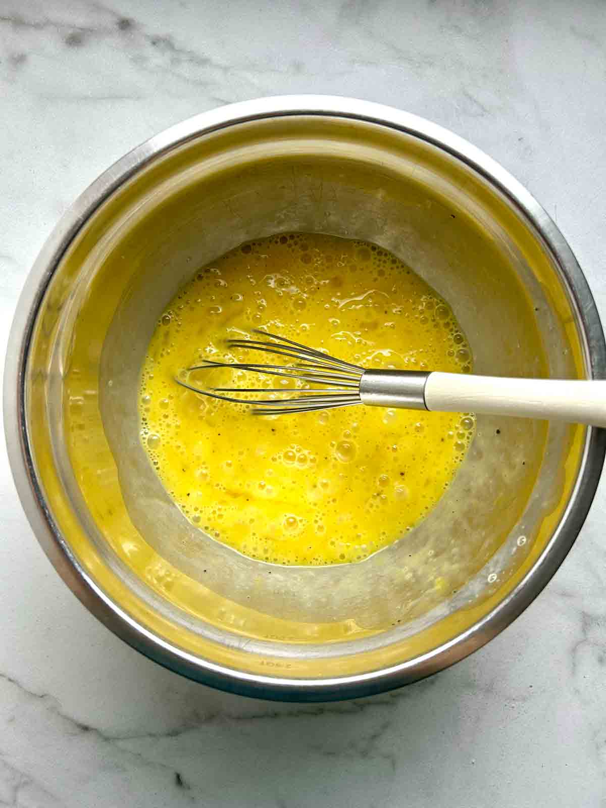 egg mixture whisked together in metal bowl.