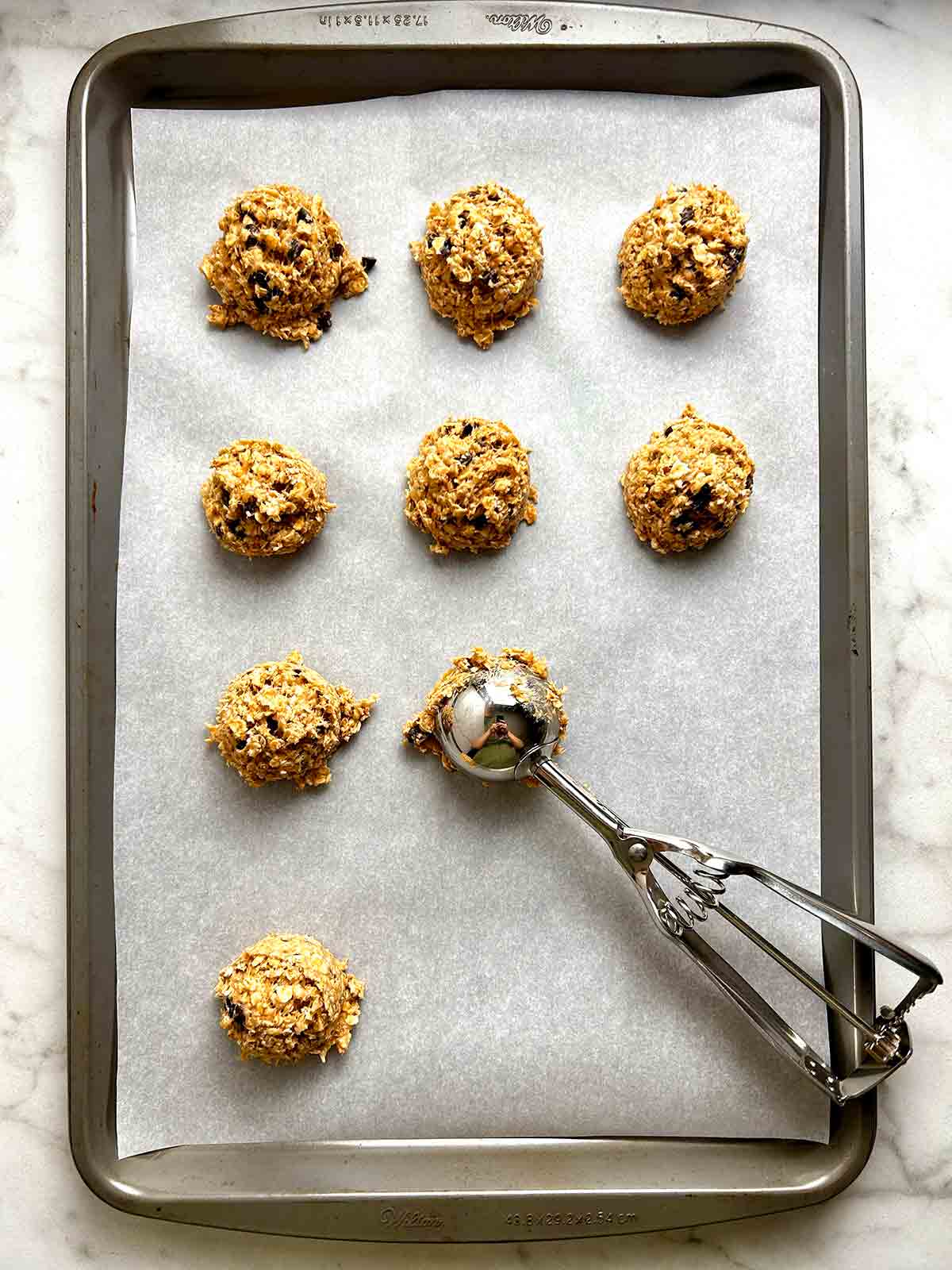 dough being portioned onto baking sheet with cookie scoop.