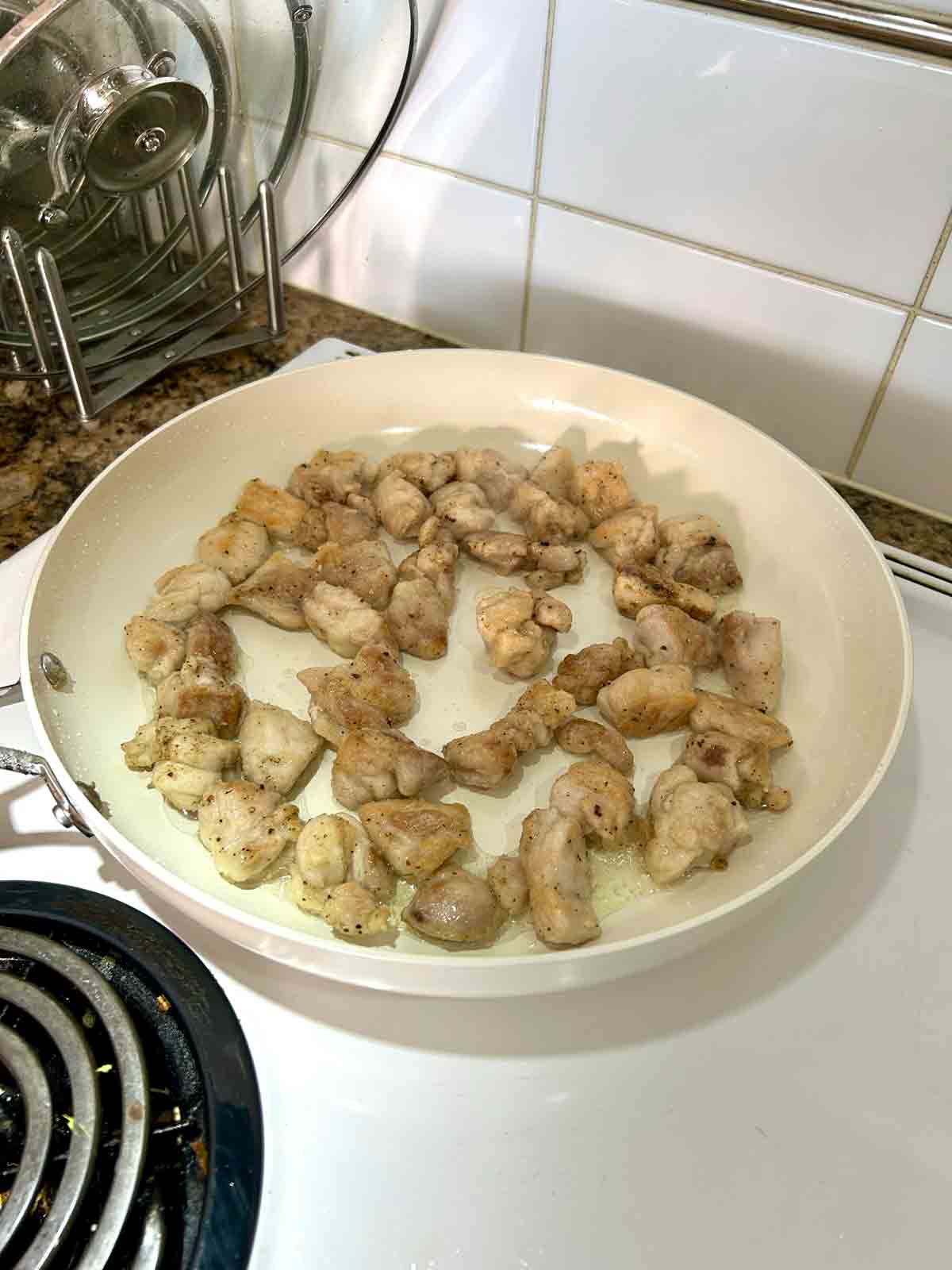 chicken being seared in skillet.
