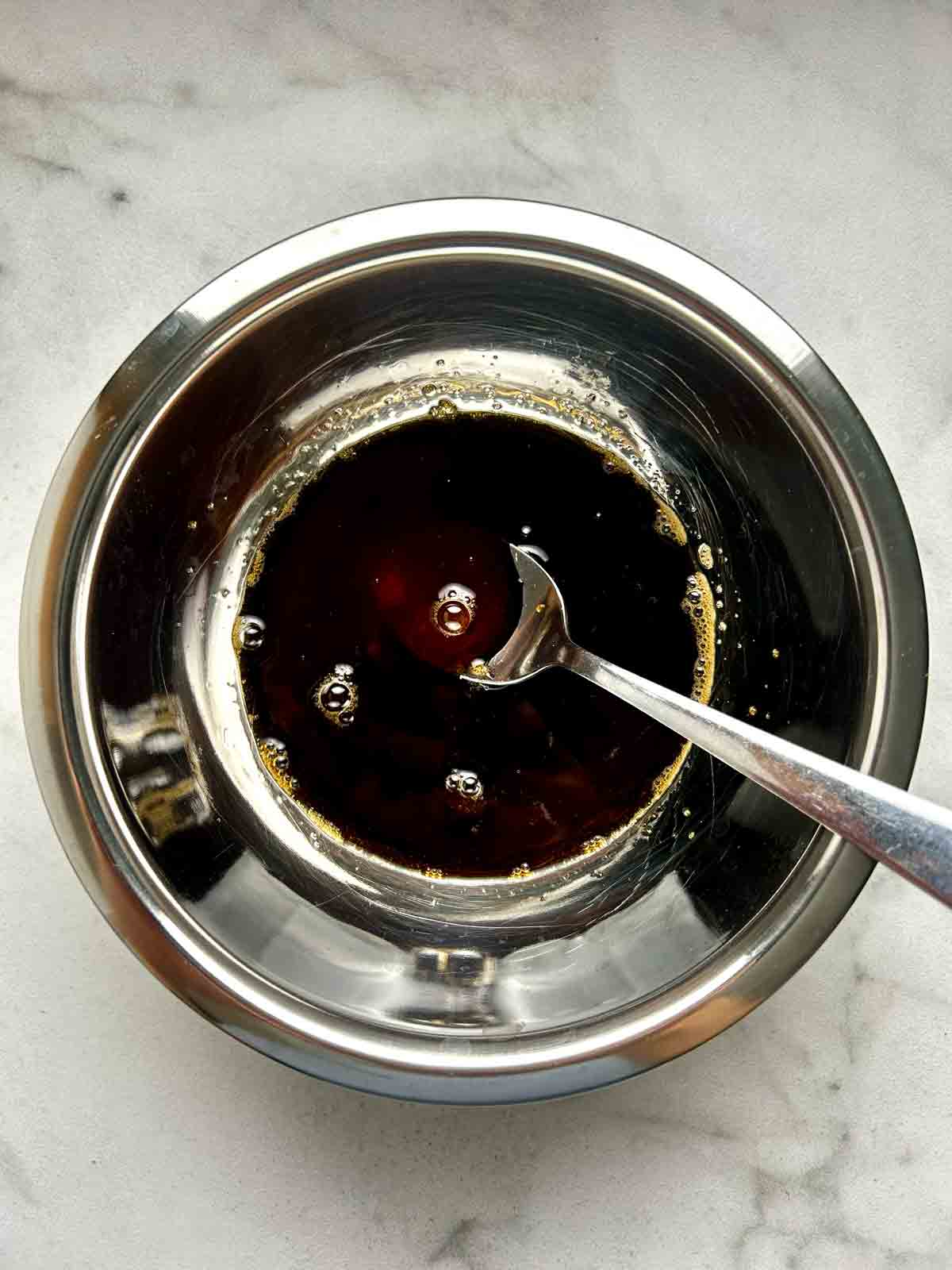 honey garlic sauce being stirred in small bowl.
