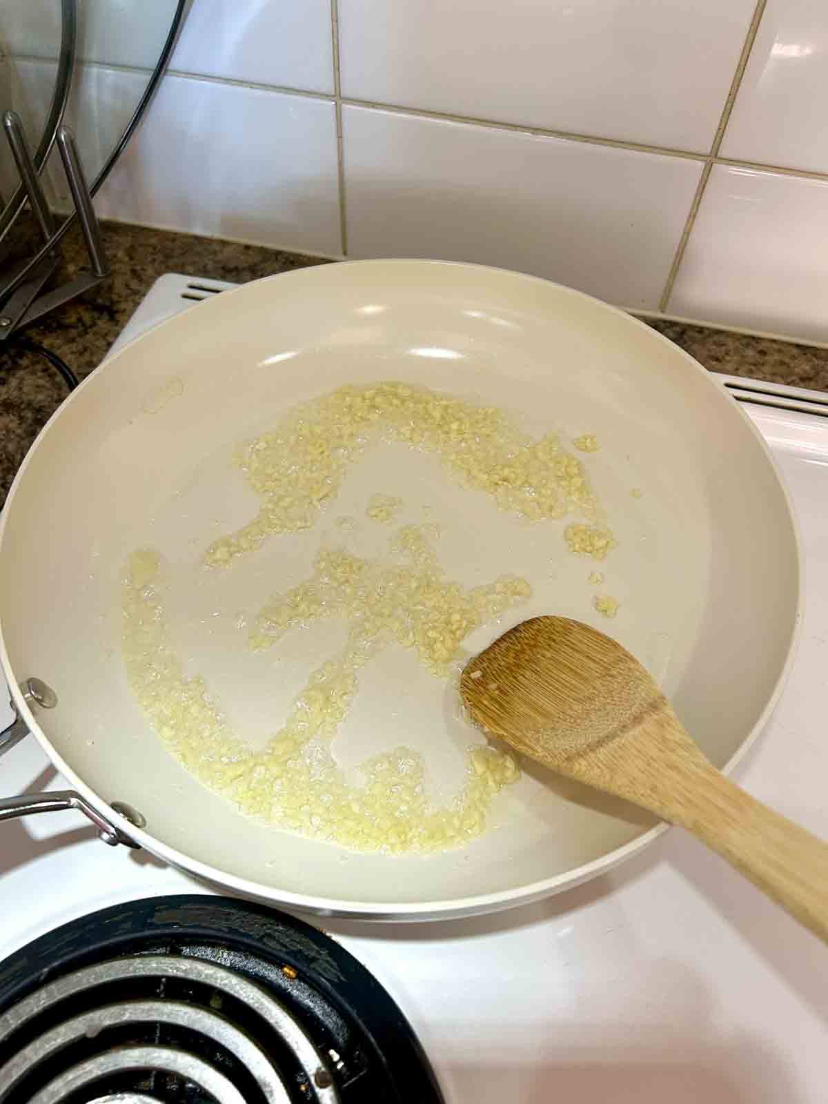 garlic being sautéed in large skillet.
