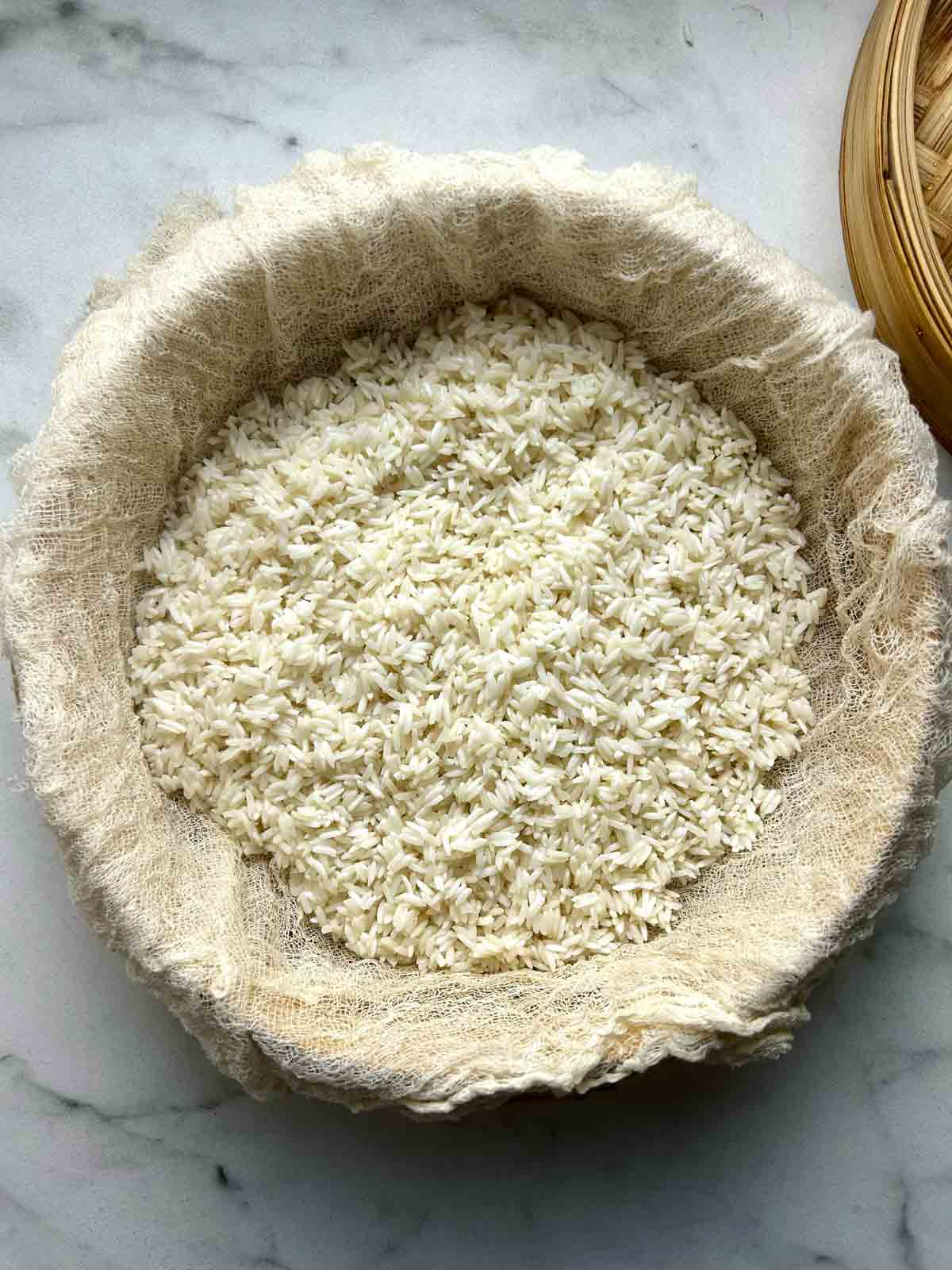 soaked rice spread evenly in cheesecloth-lined bamboo steamer.