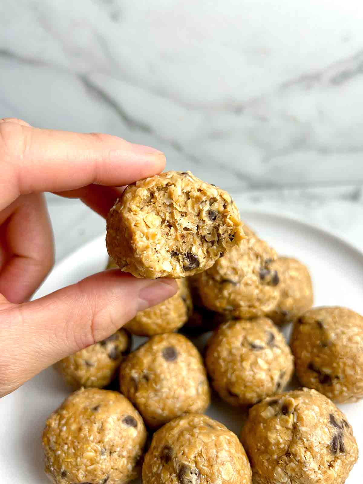 hand holding protein ball with bite taken out of it.