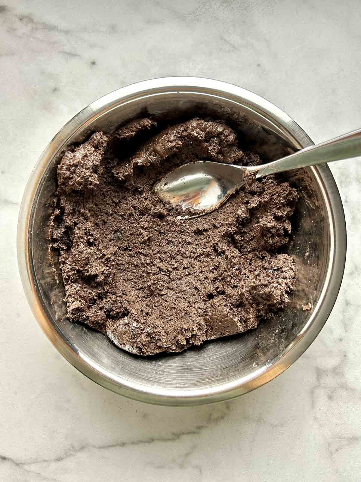 cream cheese mixed with Oreo crumbs in metal bowl.