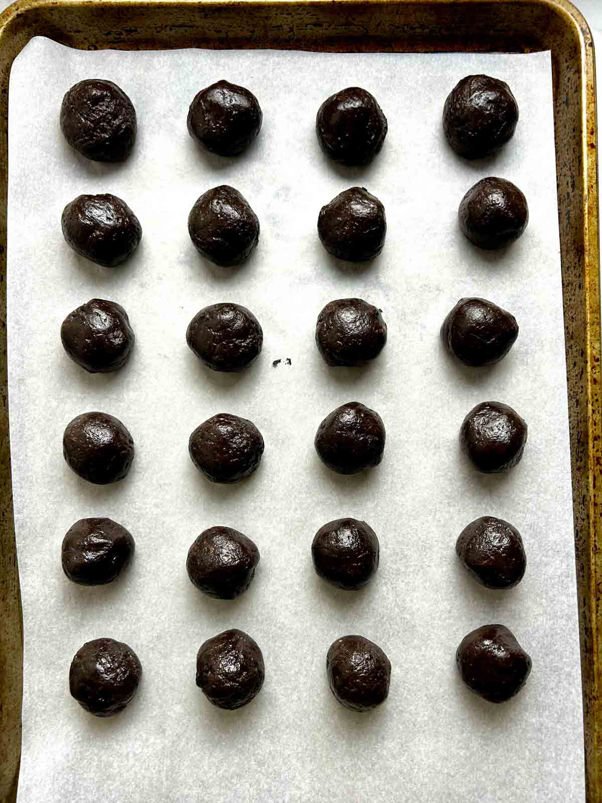 Oreo mixture shaped into balls on parchment lined baking sheet.